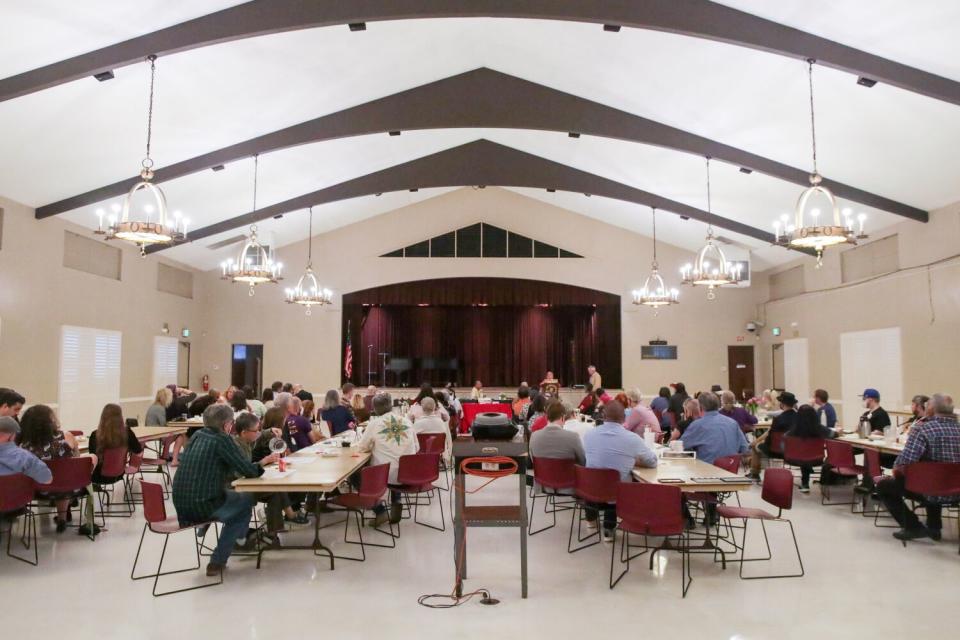 The inside of an auditorium, with people sitting at tables eating.