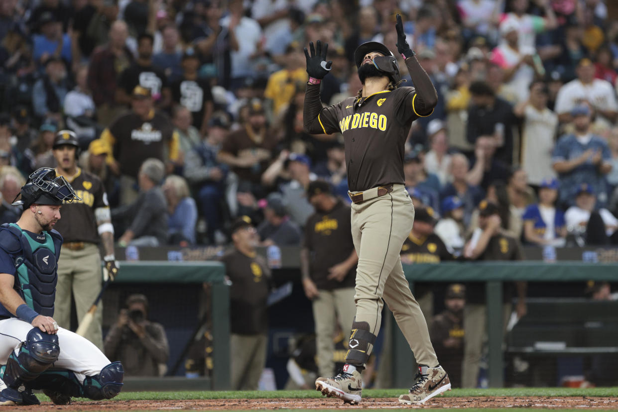 San Diego Padres' Fernando Tatis Jr. celebrates at home after hitting a three-run home run as Seattle Mariners catcher Cal Raleigh, left, looks on during the third inning of a baseball game, Tuesday, Sept. 10, 2024, in Seattle. (AP Photo/Jason Redmond)