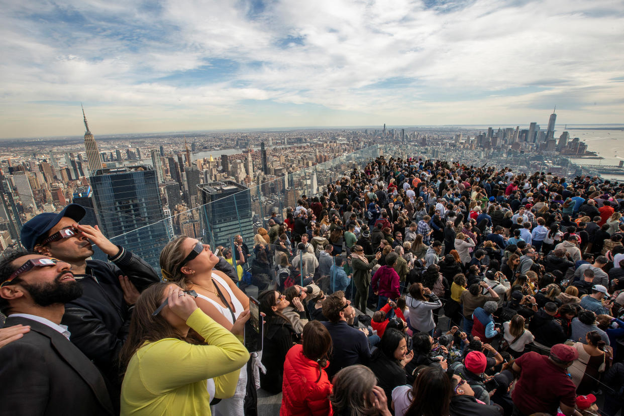 People watch the partial solar eclipse as they gather on the observation deck of Edge at Hudson Yards in New York City. 