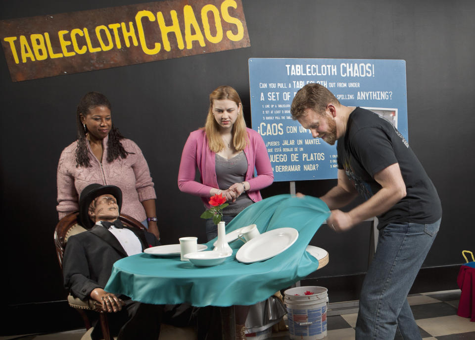 In this March 5, 2012 photo provided by the Museum of Science and Industry, friends and family of museum staff are seen at the exhibit "Tablecloth Chaos" during setup for the show "MythBusters: The Explosive Exhibition," modeled after the Discovery Channel television show "Mythbusters" at the Museum of Science and Industry in Chicago. The exhibit opens Thursday, March 15 and runs through Sept. 3. The planned national tour that will include stops at several other U.S. cities. (AP Photo/Museum of Science and Industry, J.B. Spector)