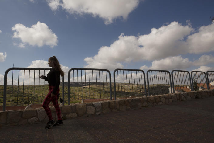 A woman takes a brisk walk in the West Bank Jewish settlement of Efrat, Friday, April 9, 2021. Israel went on an aggressive settlement spree during the Trump era, according to an AP investigation, pushing deeper into the occupied West Bank than ever before and putting the Biden administration into a bind as it seeks to revive Mideast peace efforts. (AP Photo/Maya Alleruzzo)
