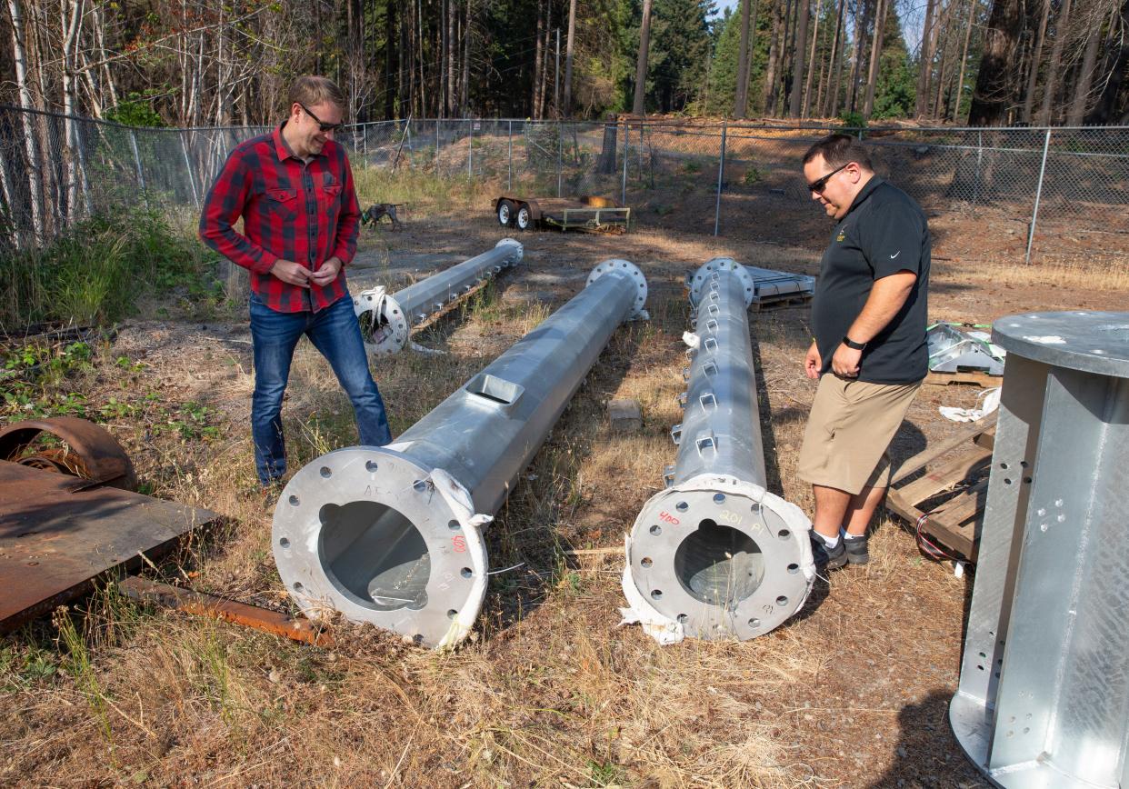 Matt Sayre, left, and McKenzie School Superintendent Lane Tompkins inspect sections of a tower in August 2021 that was set to bring broadband internet to the McKenzie River Valley.