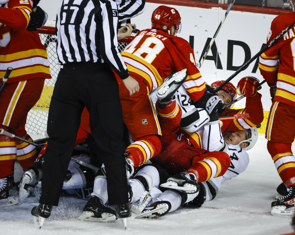 Los Angeles Kings defenseman Mikey Anderson, right, crashes to the ice with Calgary Flames forward Tyler Toffoli, center, as a scuffle breaks out in front of the net during the second period of an NHL hockey game Tuesday, March 28, 2023, in Calgary, Alberta. (Jeff McIntosh/The Canadian Press via AP)