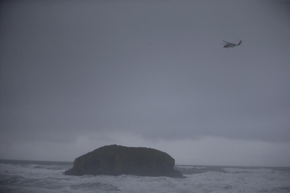 In this Sunday, Jan. 12, 2020 photo, a Coast Guard helicopter continues to search for a missing boy near Falcon Cove Beach in Clastop county, Ore. A 7-year-old girl is dead and her 4-year-old brother is missing after they and their father were swept into the ocean on the Oregon coast amid a high-surf warning. The father was holding the two children when a wave swept all three into the water Saturday, Jan. 11 in the Falcon Cove area, near the small coastal community of Cannon Beach, authorities said. (Mark Graves/The Oregonian via AP)