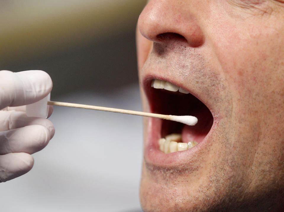 A police officer poses to illustrate a saliva test in Grevenbroich, Germany, Saturday, Nov. 23, 2019. Police in the western German city of Grevenbroich have asked about 900 men to come forward and have their DNA tested to help solve the gruesome killing of an 11-year-old girl decades ago. The girl, Claudia Ruf, was kidnapped, raped and choked to death by an anonymous murderer in 1996. (Roland Weihrauch/dpa via AP)