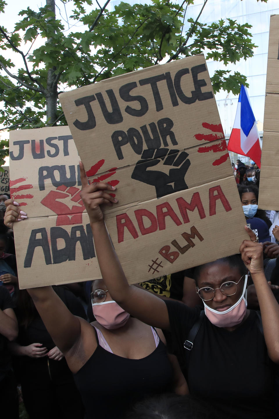 Protesters shows posters reading "Justice for Adama" outside the courthouse Tuesday, June 2, 2020 in Paris. Thousands of people defied a police ban and converged on the main Paris courthouse for a demonstration to show solidarity with U.S. protesters and denounce the death of a black man in French police custody. The demonstration was organized to honor Frenchman Adama Traore, who died shortly after his arrest in 2016, and in solidarity with Americans demonstrating against George Floyd's death. (AP Photo/Michel Euler)