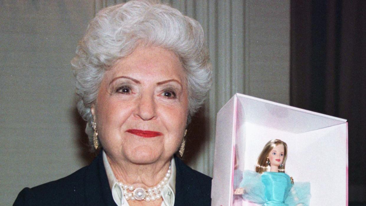 barbie creator ruth handler holding a doll inside a box and smiling for a photo