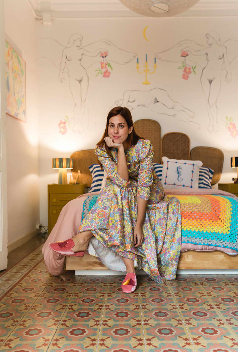 Dweller on bed with colorful quilt and floor in neutral bedroom.