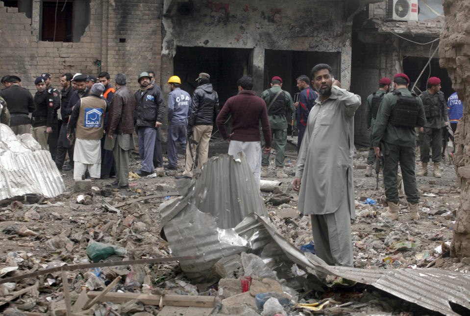 Pakistani police officers and rescue workers gather at the site of bomb blast in Peshawar, Pakistan, Saturday, Jan. 5, 2019. Pakistani police say a car bomb exploded in a Peshawar neighborhood wounding three people and damaging several shops. (AP Photo/Mohammad Sajjad)