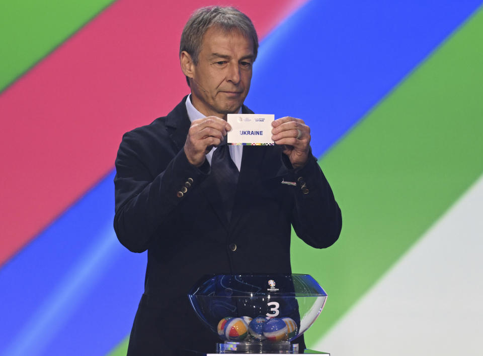 Juergen Klinsmann, former soccer player and soccer official, holds the lot of Ukraine during the draw for the groups to qualify for the 2024 European soccer championship in Frankfurt, Germany, Sunday, Oct.9, 2022. (Arne Dedert/dpa via AP)