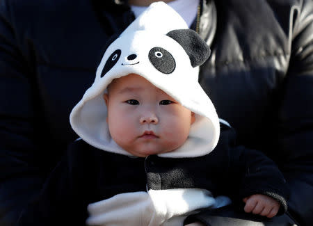 6-month-old baby Miu Suwazono wearing a costume featuring giant panda waits for starting the public debut of female baby panda Xiang Xiang, born from mother panda Shin Shin on June 12, 2017, on the first day of her public debut at Ueno Zoological Gardens in Tokyo, Japan December 19, 2017. REUTERS/Issei Kato