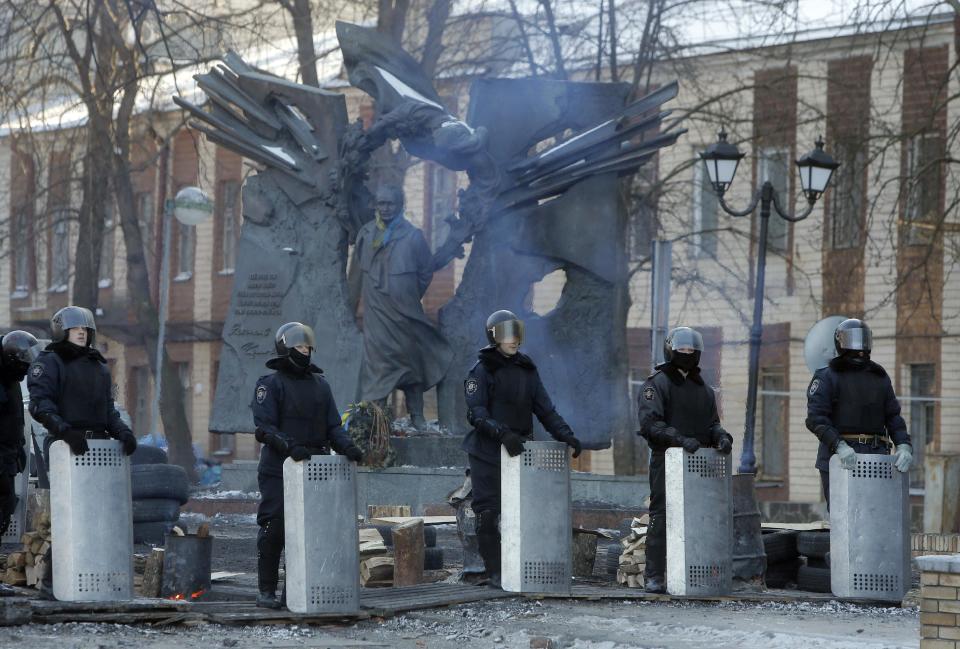 Riot police officers block a street in front of barricades and protesters at the monument to Viacheslav Chornovil, a prominent politician in Ukraine and a former Soviet political prisoner, in central Kiev, Ukraine, Sunday, Feb. 2, 2014. Kitted out in masks, helmets and protective gear on the arms and legs, radical activists are the wild card of the Ukraine protests now starting their third month, declaring they're ready to resume violence if the stalemate persists.(AP Photo/Efrem Lukatsky)