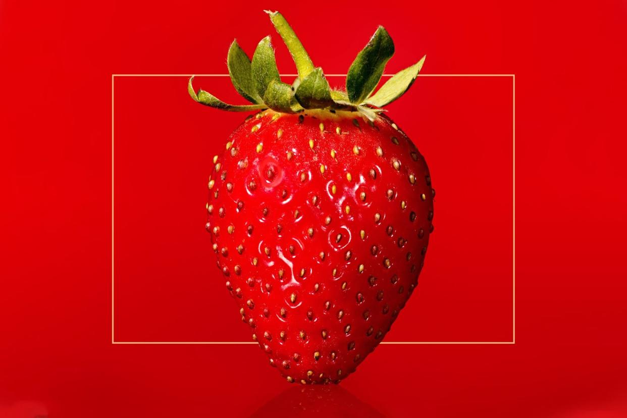 close up of a strawberry against a red background