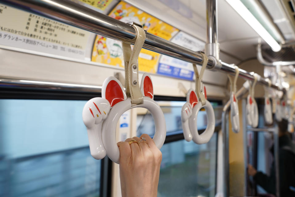 A person's hand grasping a subway strap surrounded by similar unoccupied straps