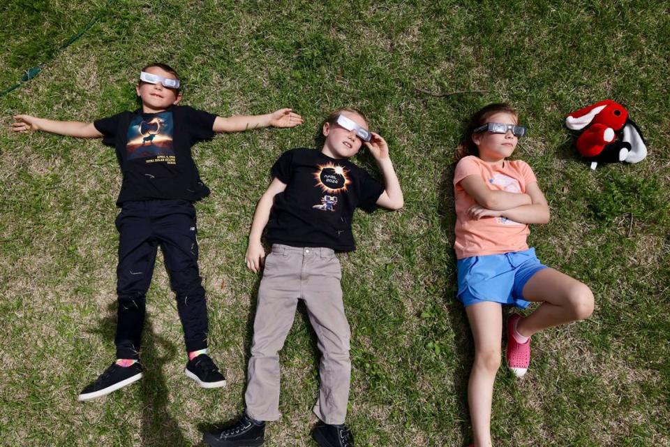 Brothers Nathan, 8 and Dean Dinino, 7, from Washington, lay down with Ada June, 8, to watch the solar eclipse outside the Hill County Courthouse on Monday, April 8, 2024, in Hillsboro. Chris Torres/ctorres@star-telegram.com