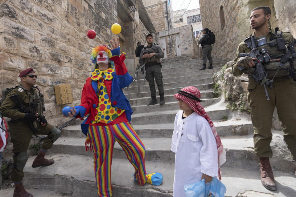 FILE - Jewish settlers dressed in costumes celebrate the Jewish holiday of Purim as soldiers secure the march in the West Bank city of Hebron, March 7, 2023. Purim celebrates the biblical story of how a plot to exterminate Jews in Persia was thwarted, and thus is embraced as an affirmation of Jewish survival throughout history. For many Jews, it will have extra significance in 2024 during a war in Gaza triggered by the Oct. 7, 2023, attacks on Israel in which Hamas killed 1,200 people and took about 250 others hostage. (AP Photo/Ohad Zwigenberg, File)