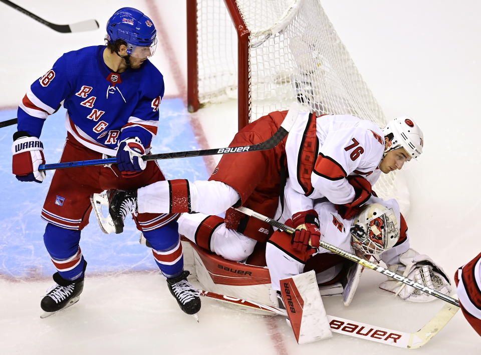 Carolina Hurricanes' Brady Skjei (76) falls on to his goaltender James Reimer (47) as New York Rangers' Brendan Lemieux (48) looks on during second period NHL Eastern Conference Stanley Cup playoff action in Toronto on Tuesday, Aug. 4, 2020. (Frank Gunn/The Canadian Press via AP)