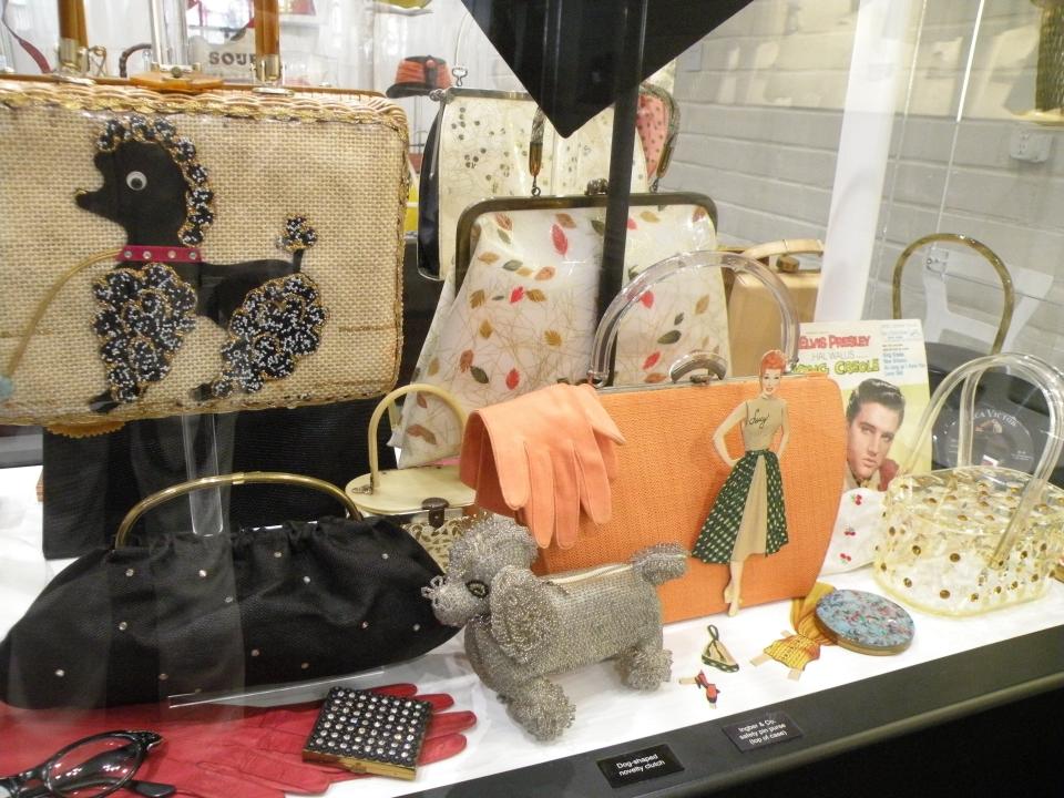 Displays at the ESSE Purse Museum and Store parade through the decades, as seen in these 1950s artifacts. The contents reflect the feminine sensibility of the decade with compact, glasses and gloves.