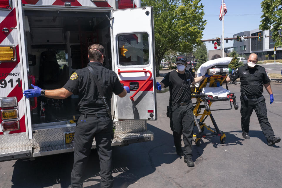 Salem Fire Department paramedics and employees of Falck Northwest ambulances respond to a heat exposure call during a heat wave, Saturday, June 26, 2021, in Salem, Ore. (AP Photo/Nathan Howard)