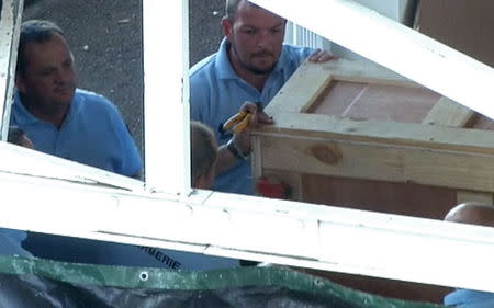 French gendarmes work on a oversized crate, believed to contain plane wreckage, in the cargo area of the airport in Saint-Denis on the French Indian Ocean island of La Reunion, in this still image taken from video shot on July 31, 2015. REUTERS/Reuters