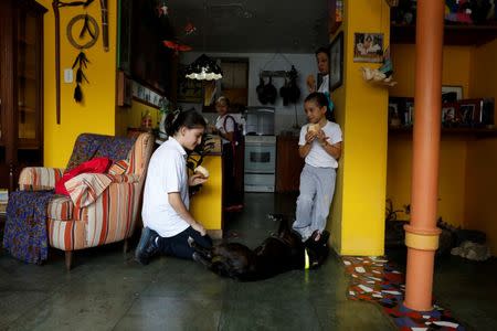 Eloisa Toro (L) and her sisters play with their dog after arriving from school on a day of protests in Caracas, Venezuela June 19, 2017. REUTERS/Carlos Garcia Rawlins