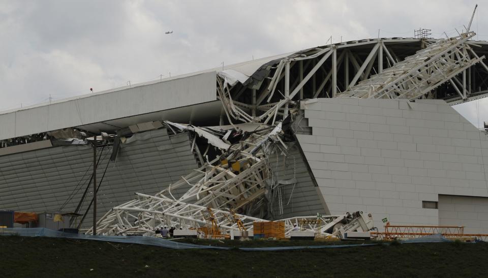 Workers stand near a crane that collapsed on the site of the Arena Sao Paulo stadium, known as "Itaquerao", which will host the opening soccer match of the 2014 World Cup, in Sao Paulo