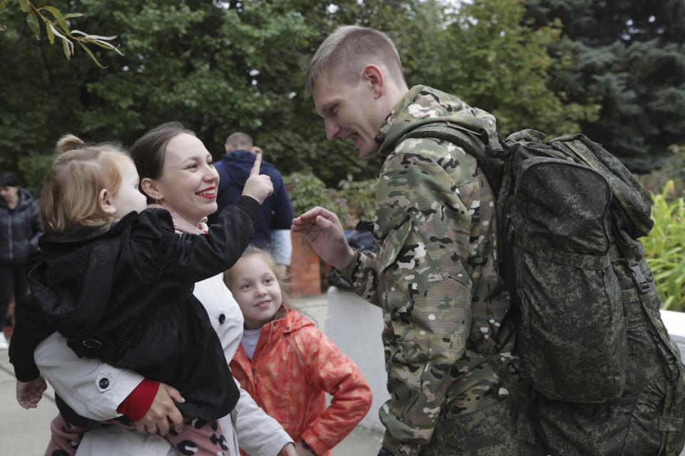 A Russian recruit speaks to his wife and children outside a military recruitment center in Volzhskiy, Volgograd region, Russia, Wednesday, Sept. 28, 2022. Russian President Vladimir Putin has ordered a partial mobilization of reservists to beef up his forces in Ukraine. (AP Photo)