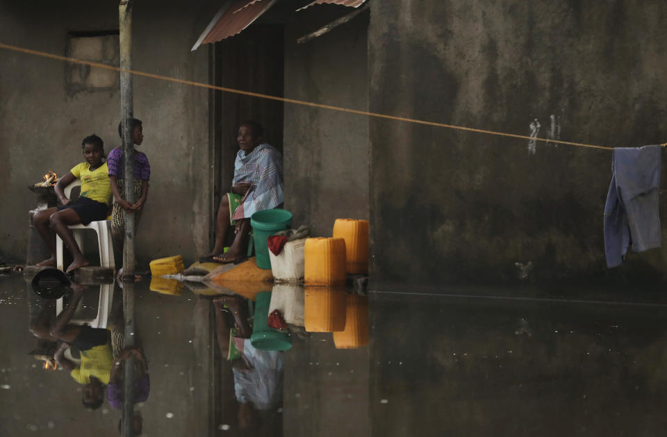 FILE - In this Sunday March 24, 2019 file photo, a family sit outside their home surrounded by water near Beira, Mozambique. Beira's mayor Davis, Simango dreamed about protecting his people from climate change with much of the city being below sea level on a coastline that experts call one of the world's most vulnerable to global warming's rising waters. (AP Photo/Themba Hadebe, File)