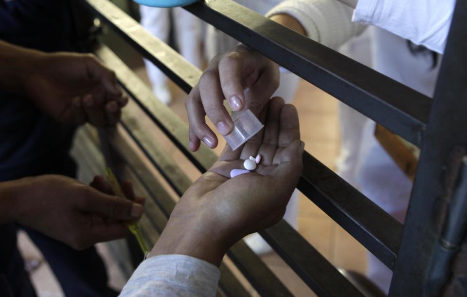 In this May 29, 2013 photo, a patient is handed medicine from a nurse at Neuro-Psychiatric Hospital bedroom in Asuncion Paraguay. Paraguay's only public psychiatric hospital is running low on medicine. It recently hit a crisis when the hospital couldn't even buy food and there were no psychiatric drugs for ambulatory patients, only inpatients, hospital director Teofilo Villalba. (AP Photo/Jorge Saenz)