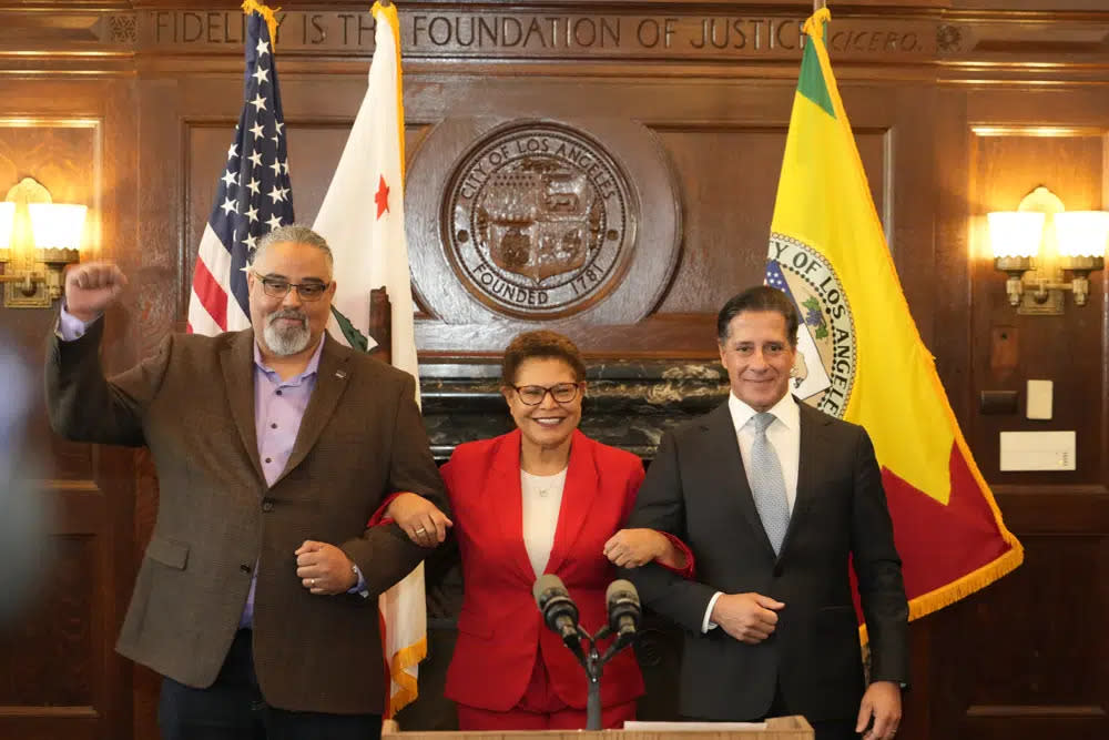 SEIU Local 99 Executive Director Max Arias, left, Los Angeles Mayor Karen Bass and District superintendent Alberto Carvalho lock in arms after announcing on a new contract together in Los Angeles City Hall Friday, March 24, 2023. (AP Photo/Damian Dovarganes)