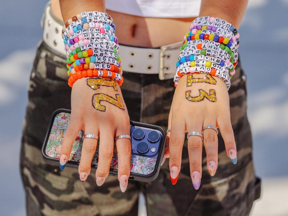 An Eras Tour attendee shows off her arms covered in friendship bracelets.