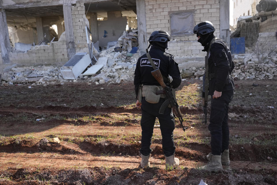 Militants of the al-Qaida-linked Hayat Tahrir al-Sham organisation stand in front of a destroyed house in Atareb, Syria, Sunday, Feb. 12, 2023. Six days after a massive earthquake killed thousands in Syria and Turkey, sorrow and disbelief are turning to anger and tension over a sense that there has been an ineffective, unfair and disproportionate response to the historic disaster. (AP Photo/Hussein Malla)