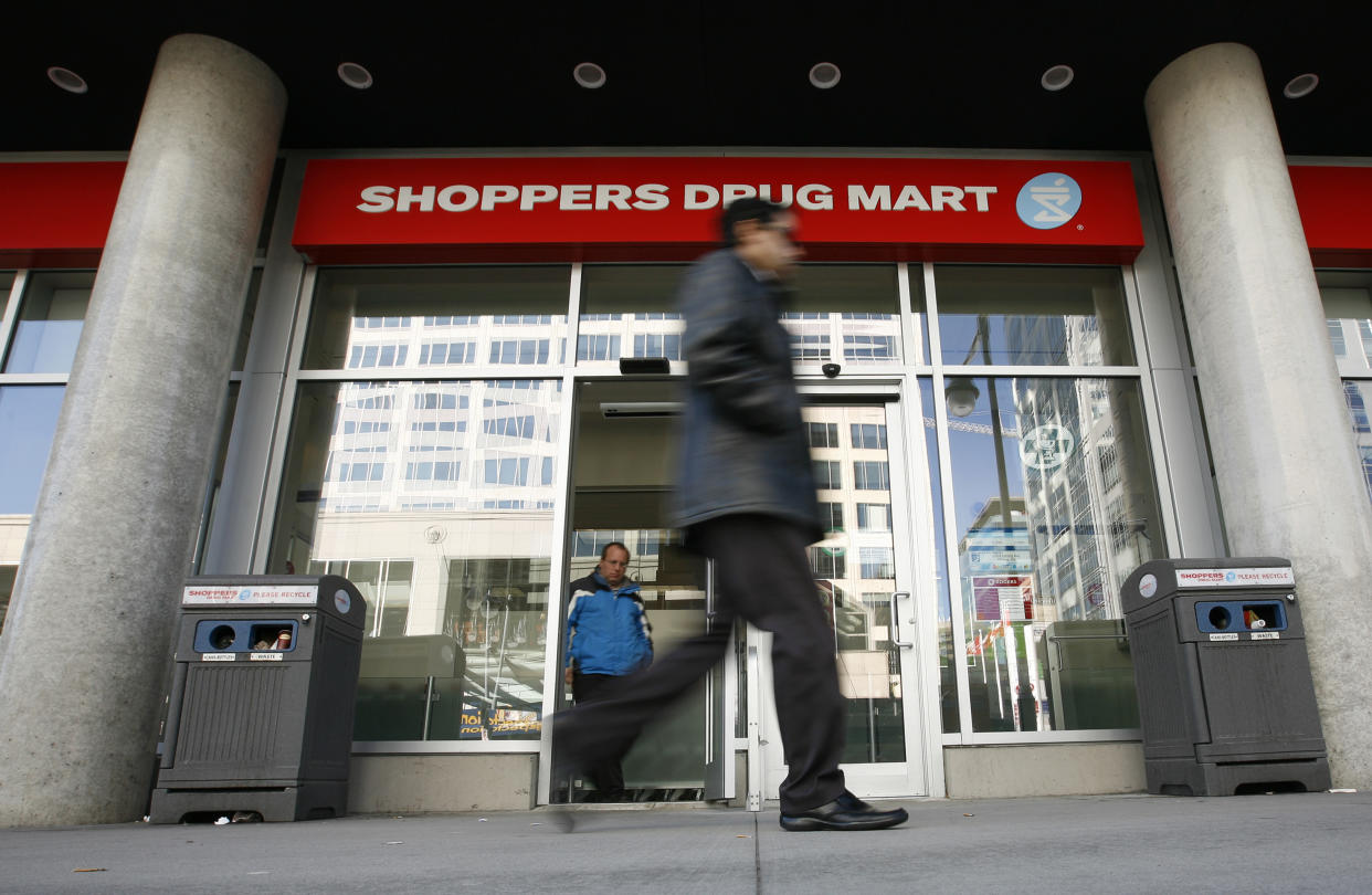 A pedestrian walks past a Shoppers Drug Mart in Ottawa November 10, 2010. Canada's No.1 pharmacy chain, on Wednesday reported a 7 percent drop in third-quarter profit and said it is facing new pressures on pricing and government reimbursement.       REUTERS/Chris Wattie       (CANADA - Tags: BUSINESS)