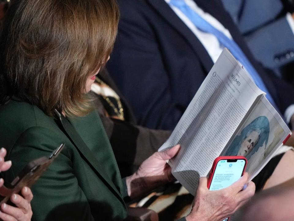 Rep. Nancy Pelosi, D-Calif., looks at a magazine article that has a picture of Rep. Kevin McCarthy, R-Calif., on it as the House votes in the fourth round of voting for a second day are they try to elect a speaker and convene the 118th Congress in Washington, Wednesday, Jan. 4, 2023.
