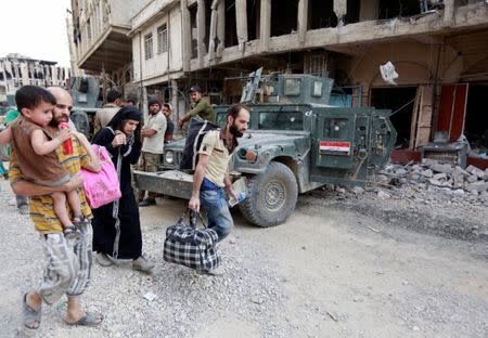 Displaced Iraqi people, who fled from clashes, carry their luggage during fighting between Iraqi forces and Islamic State militants in the Old City of Mosul, Iraq July 7, 2017. REUTERS/Ahmed Saad