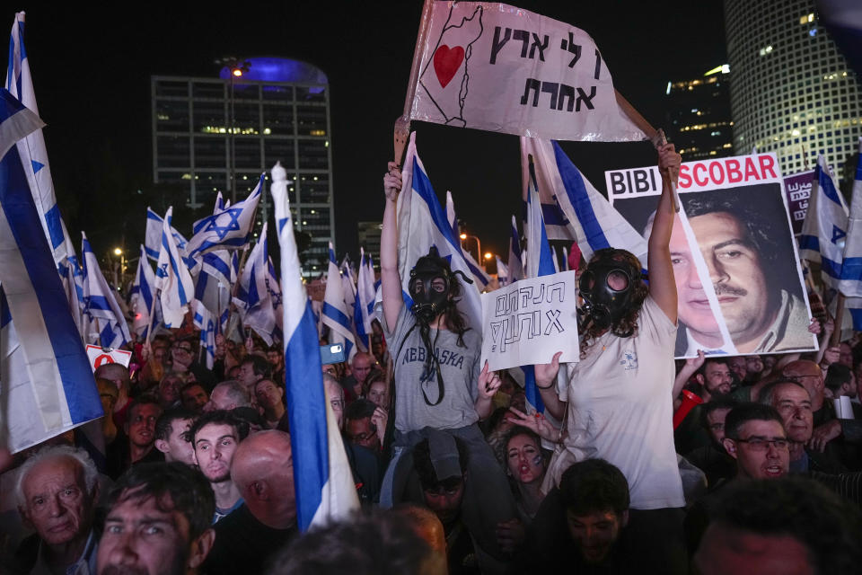 Demonstrators wear gas masks during a protest against plans by Israeli Prime Minister Benjamin Netanyahu's new government to overhaul the judicial system, in Tel Aviv, Israel, Saturday, March 4, 2023. Hebrew on banners read "I have no other country", " You suffocated us". (AP Photo/Ohad Zwigenberg)