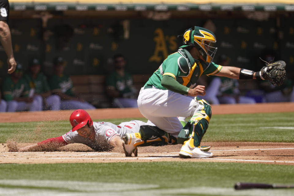 Los Angeles Angels' Max Stassi scores at home plate as Oakland Athletics catcher Aramis Garcia waits for the throw in the first inning of a baseball game Wednesday, June 16, 2021, in Oakland, Calif. Stassi scored after the Angels' Taylor Ward singled to left field. (AP Photo/Eric Risberg)