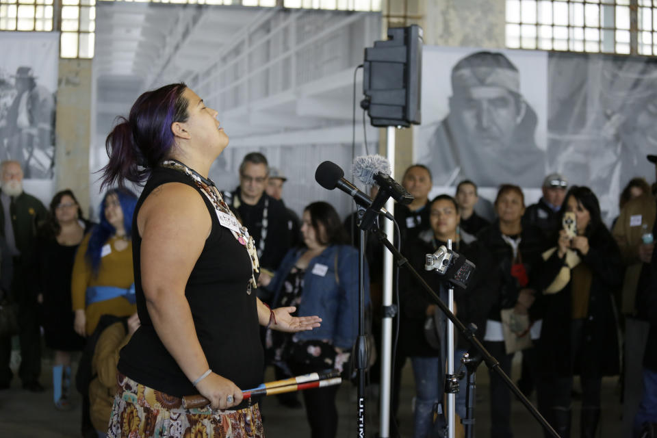 Kanyon Sayers-Woods sings during ceremonies marking the 50th anniversary of the Native American occupation on Alcatraz Island Wednesday, Nov. 20, 2019, in San Francisco. About 150 people gathered at Alcatraz to mark the 50th anniversary of a takeover of the island by Native American activists. Original occupiers, friends, family and others assembled Wednesday morning for a program that included prayer, songs and speakers. They then headed to the dock to begin restoring messages painted by occupiers on a former barracks building. (AP Photo/Eric Risberg)