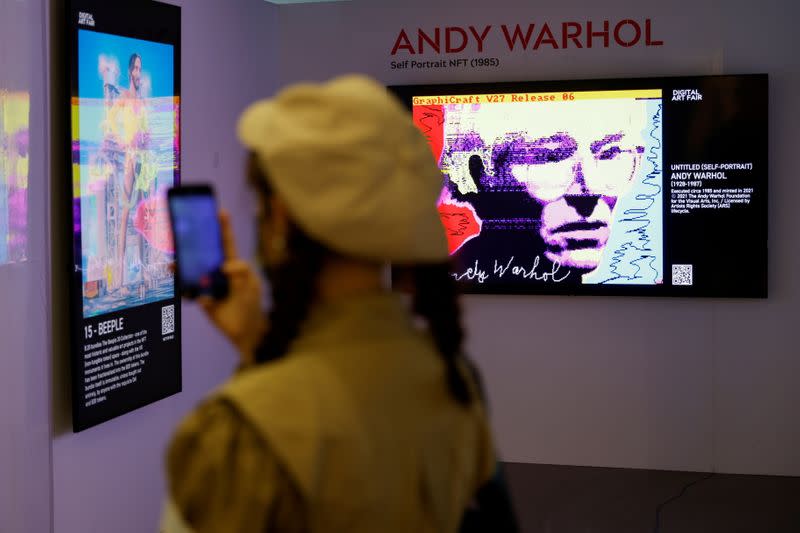 FILE PHOTO: Visitor takes a photo in front of digital works at the Digital Art Fair in Hong Kong