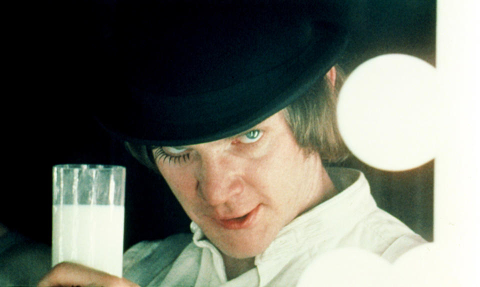 A character holding up a glass of milk and staring intensely at the camera