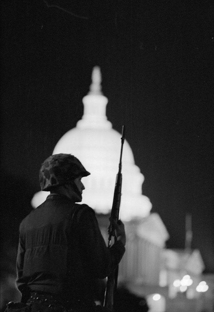 View, from behind, of an armed soldier, in a camouflage helmet, as he enforces a nighttime curfew outside the US Capitol after riots in the wake Dr Martin Luther King Jr’s assassination, Washington DC, April 8, 1968.