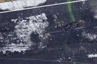 The burn-out Japanese coast guard aircraft is seen, right, at Haneda airport on Wednesday, Jan. 3, 2024, in Tokyo, Japan. A large passenger plane and the Japanese coast guard aircraft collided on the runway at Tokyo's Haneda Airport on Tuesday and burst into flames, killing several people aboard the coast guard plane, officials said. (Kyodo News via AP)