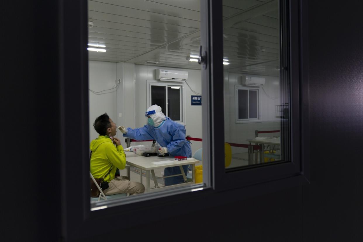 A medical worker collects a swab sample from a man in a COVID-19 testing facility.