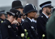 A police officer wipes her face as she holds a rose during an event to mark one week since a man drove his car into pedestrians on Westminster Bridge then stabbed a police officer in London, Britain March 29, 2017. REUTERS/Hannah McKay