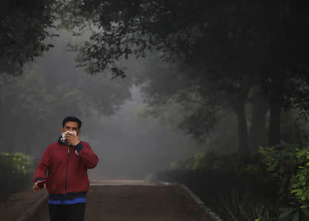 A man covers his face with a handkerchief as he walks ina park on a smoggy morning in New Delhi, India, November 9, 2017. REUTERS/Saumya Khandelwal