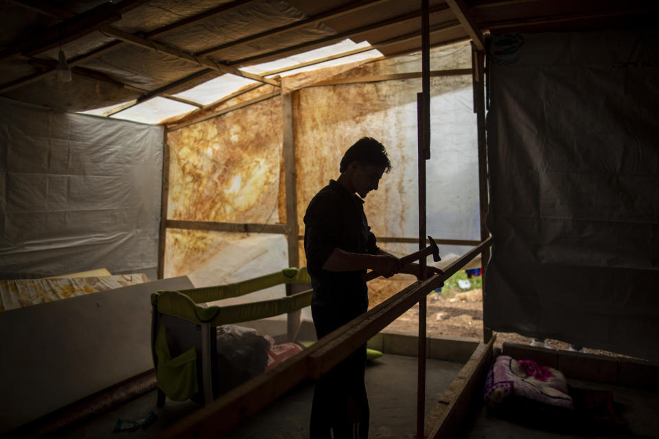 Syrian refugee Raed Mattar, 24, works on his tent, at an informal refugee camp, in the town of Rihaniyye in the northern city of Tripoli, Lebanon, Thursday, April 8, 2021. For many Syrian refugee families in Lebanon, Ramadan comes as a hard life of displacement has gotten even harder after a pandemic year that deepened economic woes in their host country. (AP Photo/Hassan Ammar)