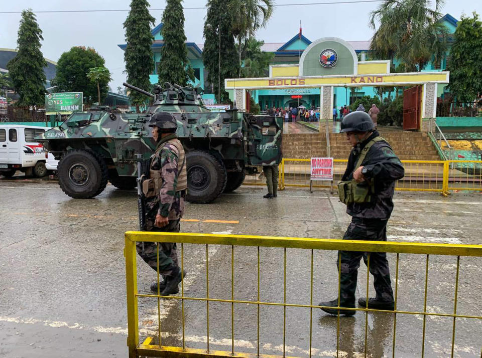 Soldiers walk near an armored personnel carrier parked outside the Saguiaran city hall in Lanao del Sur province, southern Philippines, Monday, Jan. 21, 2019. Muslims in the southern Philippines voted Monday in a referendum on a new autonomous region that seeks to end nearly half a century of unrest, in what their leaders are touting as the best alternative to a new wave of Islamic State group-inspired militants. (AP Photo/Bogie Calupitan)