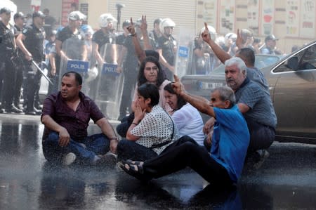 Demonstrators react as police try to disperse them during a protest against the replacement of Kurdish mayors with state officials in three cities, in Diyarbakir