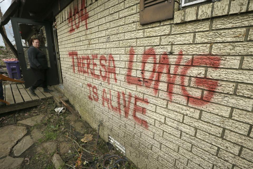 Theresa Long walks into her storm-damaged home in Mayflower, Ark., Tuesday, April 29, 2014. Long painted a sign reading "Theresa Long is Alive" on the front of the house after a Sunday tornado struck the neighborhood. (AP Photo/Danny Johnston)