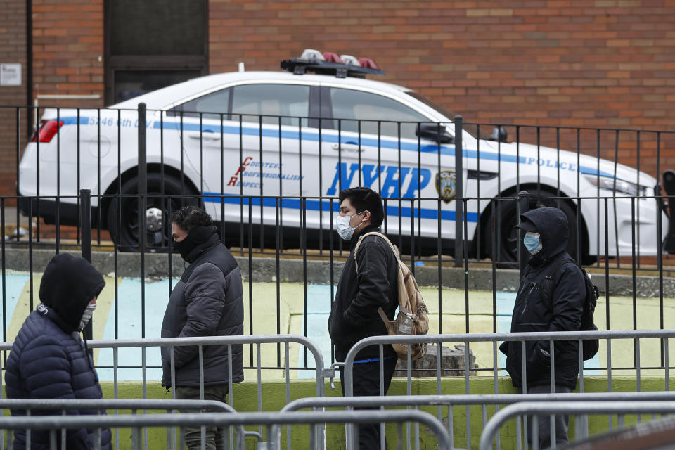 Patients wearing personal protective equipment stand on line while maintaining social distancing before entering a COVID-19 testing site at Elmhurst Hospital Center, Wednesday, March 25, 2020, in New York. Gov. Police have stepped up efforts to pressure New Yorkers to practice social distancing at the epicenter of the crisis. It's part of a global challenge that law enforcement and health officials say is critical to containing the coronavirus. (AP Photo/John Minchillo)